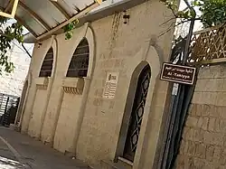 The exterior of Al-Takiya, its name visible on the sign, a sign referencing the Turkish Cooperation and Coordination Agency can also be seen