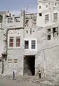 The image shows two houses within Qatif Castle, each consisting of three floors with a corridor between them and a basement underneath. The photograph was taken in 1975.