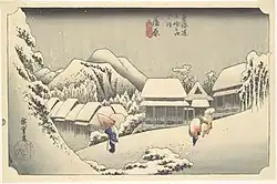A village in a mountainous landscape. A man with a conical hat and a cane, and a saddled horse can be seen in the foreground. Japanese characters are seen in the down left and top central parts of the image.