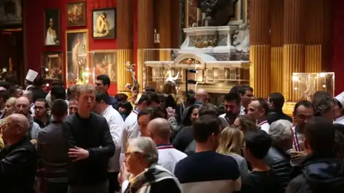 In the foreground, many people looking at exhibits. In the background, the large dramatic exhibits. The room appears to be a museum in lush colors