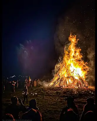 A burning bonfire of a towering 30 foot wickerman holding a sword. A crowd watches from below.