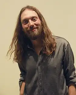 Mike Dawes wearing a grey long-sleeved shirt, looking directly at camera and smiling