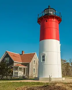 Red and white lighthouse next to a house