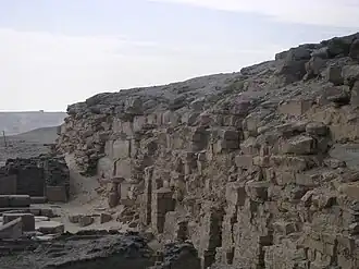 Ruined wall of bricks and a few stones in the desert.