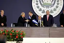 A photograph of Mauricio Funes wearing the presidential sash with Salvador Sánchez Cerén