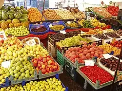 Dozens of baskets of brightly colored fruits and vegetables stacked around intersecting aisles at a market.