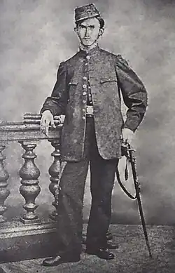 Picture of Decoud in military uniform, with a sword, standing over a railing