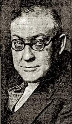 Black-and-white newspaper headshot of Walter Hackett. He then was a clean-shaven, middle-aged, white man with glasses and a suit.