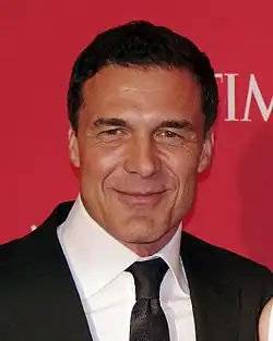 André Balazs in a black suit, standing against a branded backdrop