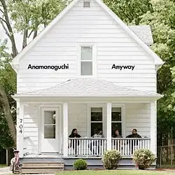 A white house surrounded by foliage, with all four members of the band Anamanaguchi on the front porch.