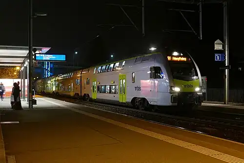 Green-and-white train at station with canopy-covered platform