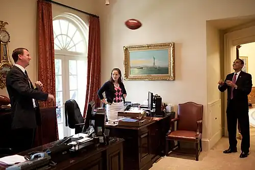 President Barack Obama tosses a football with Trip Director Marvin Nicholson in the outer Oval Office on June 26, 2009. Personal Secretary Katie Johnson watches from her desk.