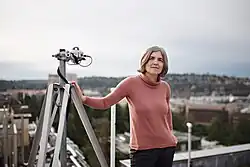 woman with telescope standing on top of building
