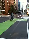 Green cycle lane transitioning into a cycle track with concrete barriers after an intersection in Ottawa, Ontario, Canada (Laurier Avenue) in 2011.