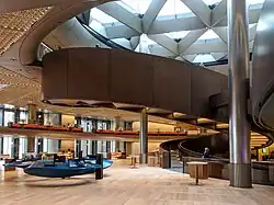 Interior of an office building with a large spiral bronze coloured ramp between floors