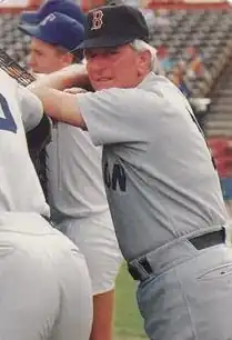 A man in a gray baseball uniform and black cap