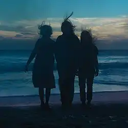 Three silhouettes of women standing on the beach