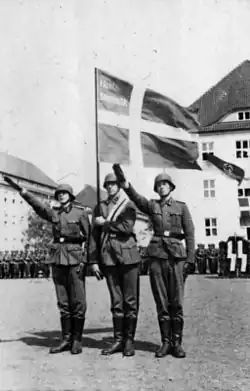a black and white photograph of soldiers performing the "Hitler salute" beneath a Danish flag