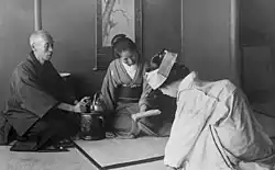 A black and white photo of a Japanese bride in traditional attire greeting her elders