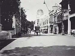 Photograph of a horse and cart on a road with an old ornate building in the background