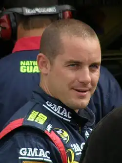 Semi-profile of a man in his late-twenties, clean shaven and smiling.
