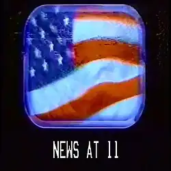 A windy American flag seen through a plane window; below reads "NEWS AT 11" in a font used by the US military.