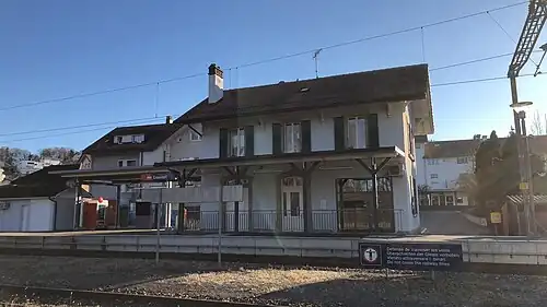 Two-story building with gabled roof and adjoining canopy-covered shelter