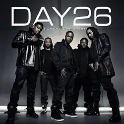 The cover shows the group standing in a grey room, wearing various black clothing. The group's name and the album title appear behind them in white lettering.