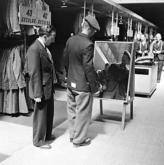 Private Bill Krepper of the Pioneer Corps is assisted in the selection of his demob suit.