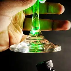 Total internal reflection of a green laser in the stem of a wine glass