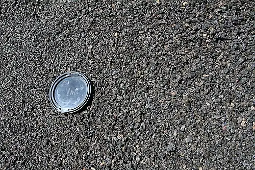 Cinders of the cone of Caldera de los Cuervos on Lanzarote, with camera lens cap (77 mm (3 in) across) for scale