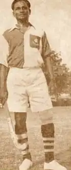 A Black and White photo of man holding hockey stick in his right hand.