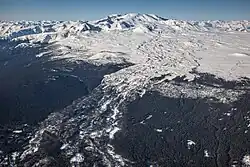 A partially snow-covered plateau with mountains in the background