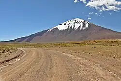 A snow-covered, barren mountain rising from a road