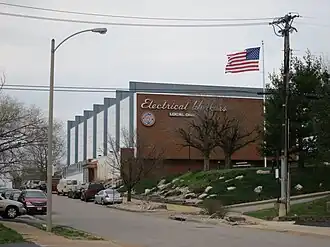 A building with brick side and fins on the front with a flag in the foreground