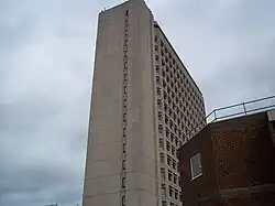 view upwards to tall pale multi-storey building under a cloudy sky