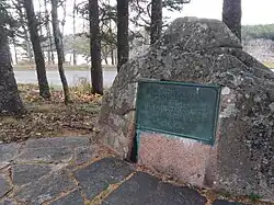 A placque affixed to a mound of granite.