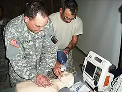 Two men perform CPR on a CPR doll