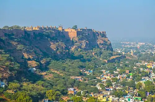 A large clifftop fortress with massive walls, high above buildings down the hill