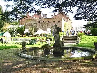 a circular pool with a statue in the centre of it, the house is in the background