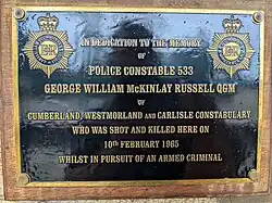 In dedication to the memory of Police Constable 533 George William McKinlay Russell QGM of Cumberland, Westmorland and Carlisle Constabulary who was shot and killed here on 10th February 1965 whilst in pursuit of an armed criminal.