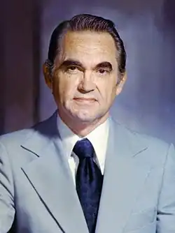 Official portrait of Wallace, wearing a light blue suit jacket, white shirt, and dark blue necktie.