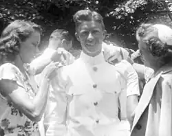 Jimmy Carter smiling towards the camera, while Rosalynn Smith and his mother are fixing his Naval Academy uniform