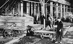 Pouring slag at water jacket furnace (1905). Copper matte is being tapped into the smaller vessel on the left (lower spout).