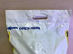 Plastic bag of water softener salt; handle die-cut through the thick plastic to allow carrying