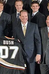 Henry Samueli wearing a black suit presenting a black hockey jersey labeled "Bush 07" to President George W. Bush.