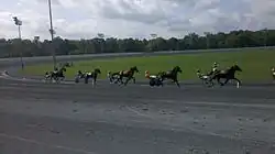 There are six horses racing at Rosecroft Raceway during a qualifying race.