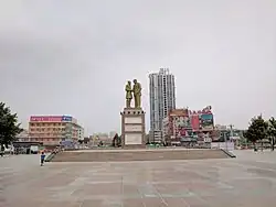A monument depicting Kurban Tulum shaking hands with Mao Zedong stands in the centre of Tuanjie Square.