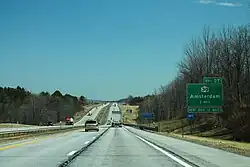 A divided highway with two lanes in each direction, seen on a straightaway with trees off to the sides