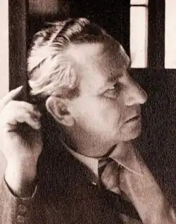 A man in later middle age, in a formal suit and tie, looking to the camera's right, leaning on his right elbow.